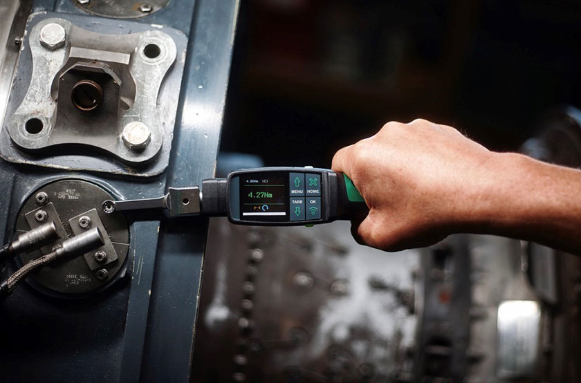 Digitaler Drehmomentschlüssel mit Einsteckwerkzeug beim Anziehen einer Verschraubung an einer Maschine