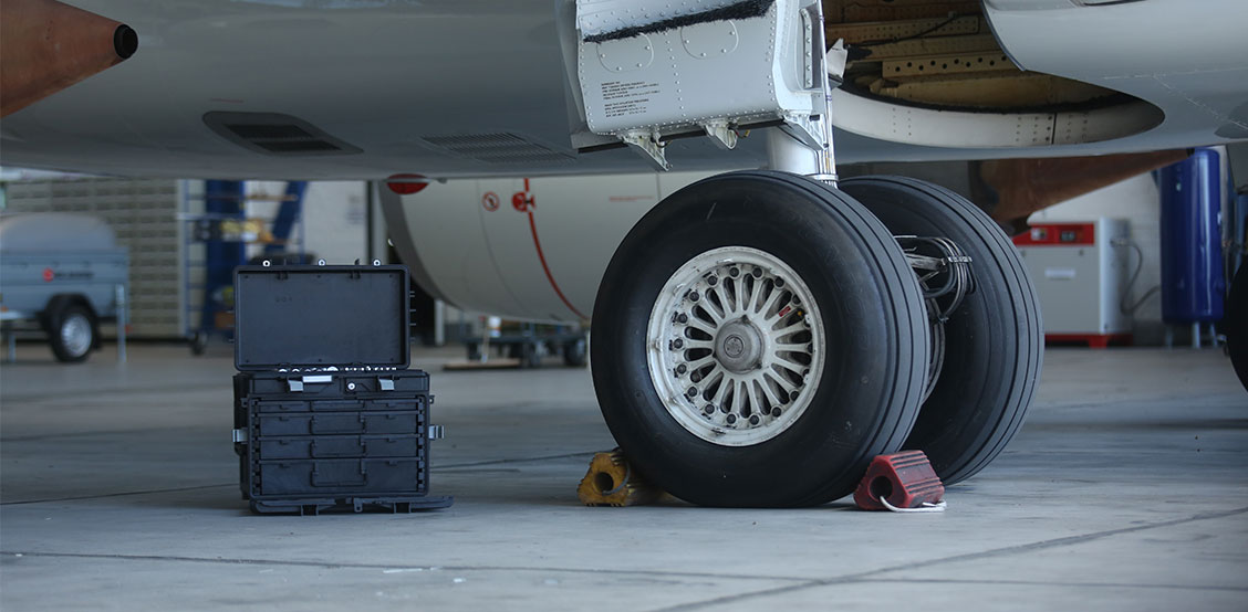 Carretilla portaherramientas móvil STAHLWILLE con tapa abierta delante de un avión en el hangar, ideal para el mantenimiento y servicio en la aviación.