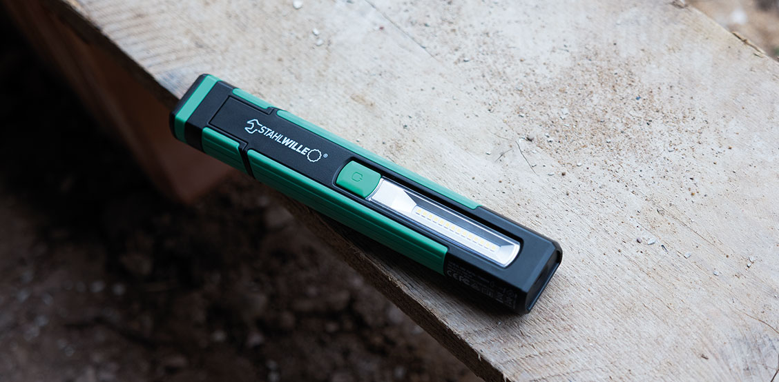 STAHLWILLE LED hand lamp in green and black design on a wooden beam.